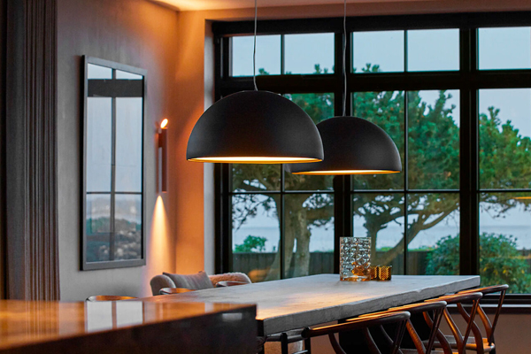 A dining room with two large white pendant lights hanging above a wooden dining table.